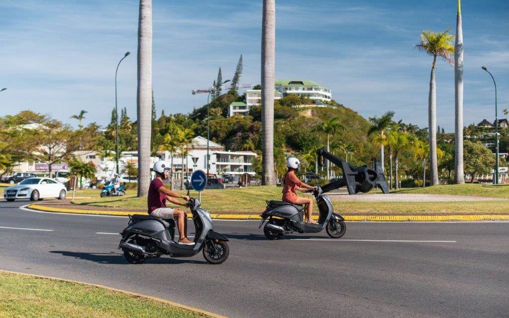Deux scooters passent un rond-point de Nouméa